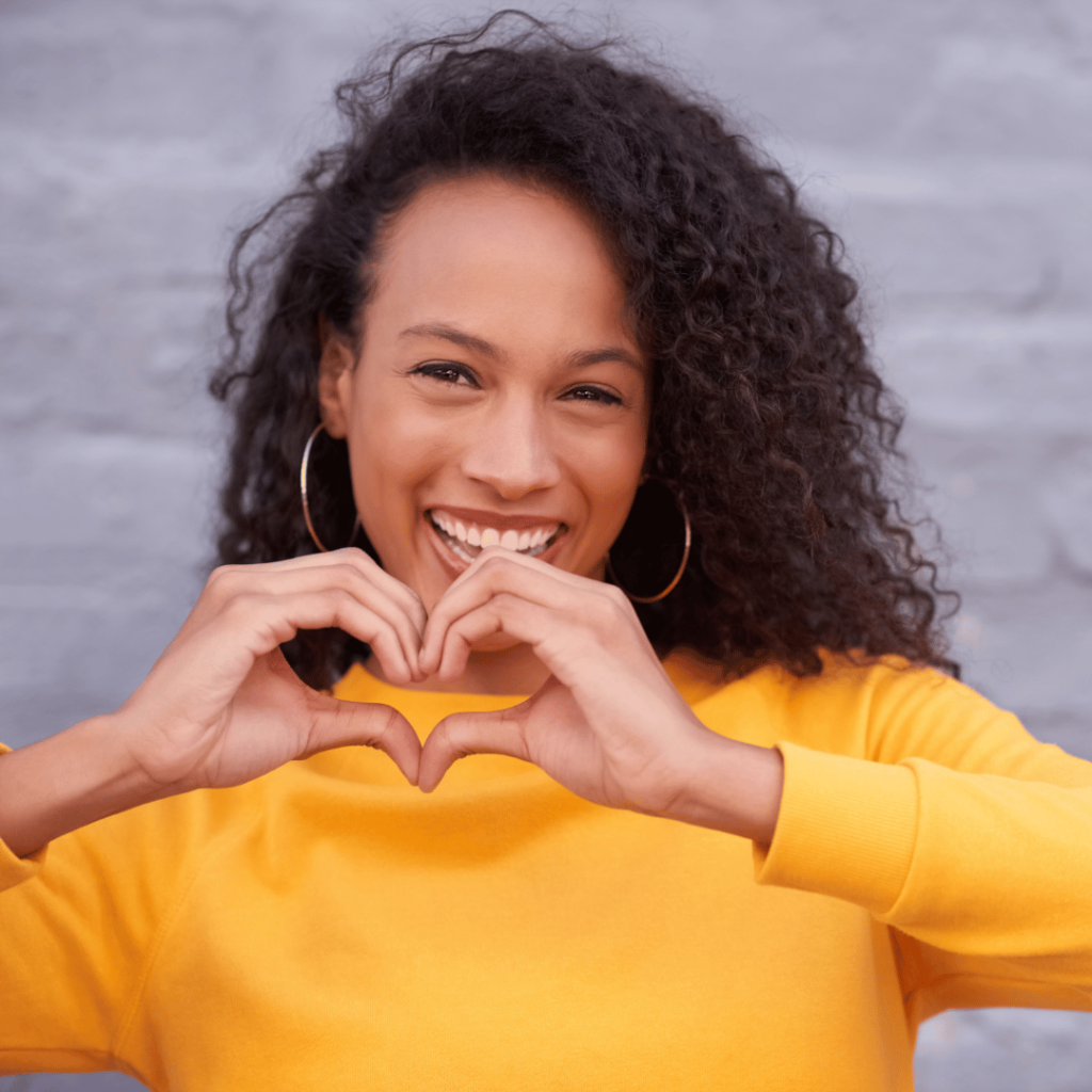 kind woman making heart symbol with hands