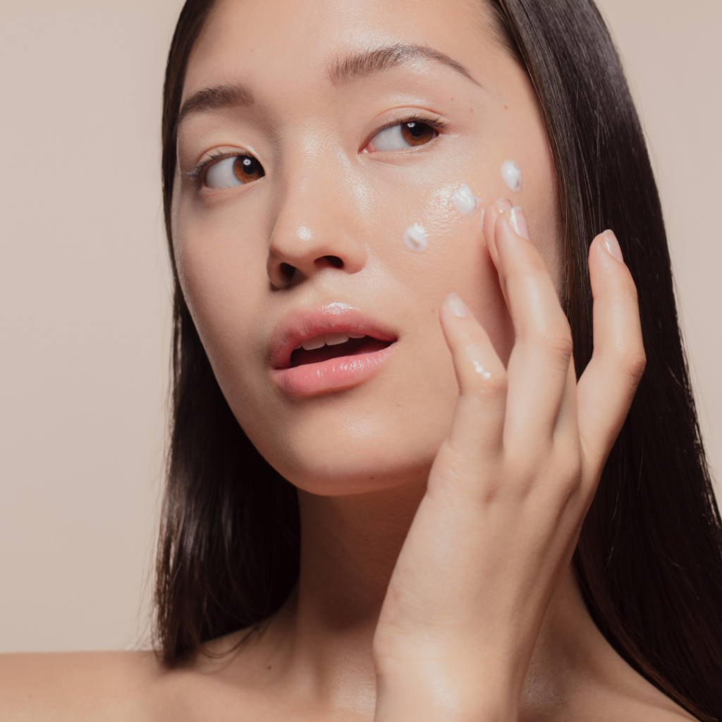 woman applying moisturizer to cheeks