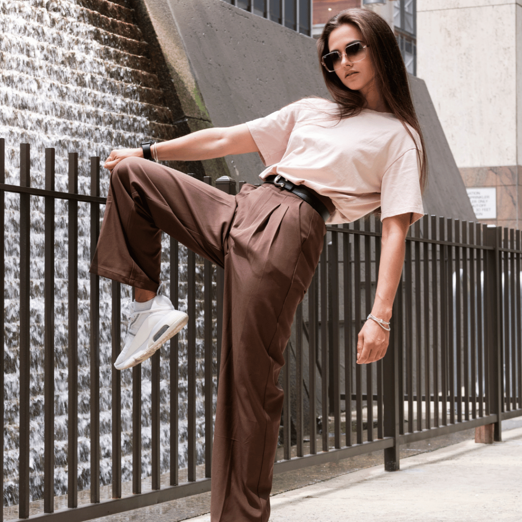 stylish woman posing next to a fence